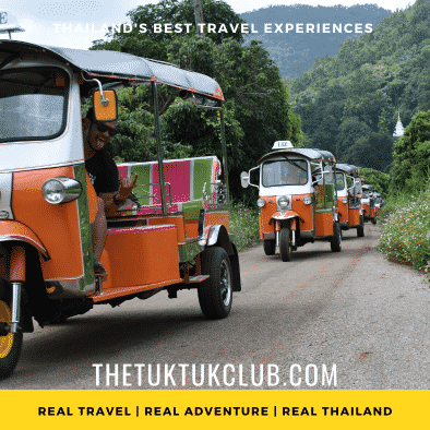 Five Tuk Tuks in convoy on a Thailand adventure driving down a small road with mountains and forest in the background