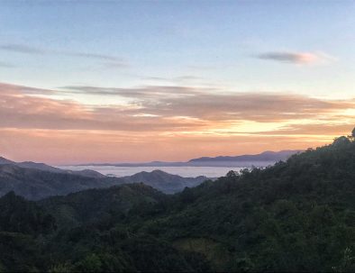 The sun setting over forested mountain in Northern Thailand with a misty valley in the distance